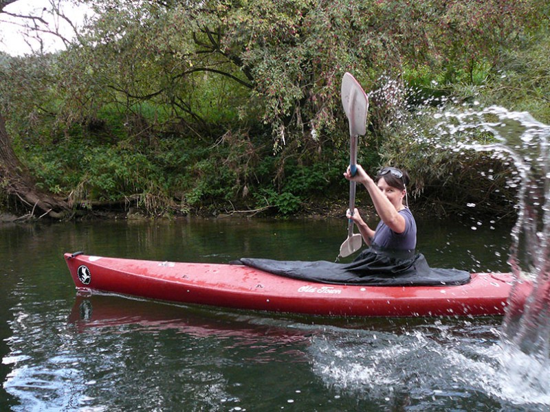 Frau im Einerkajak spritz mit Paddel