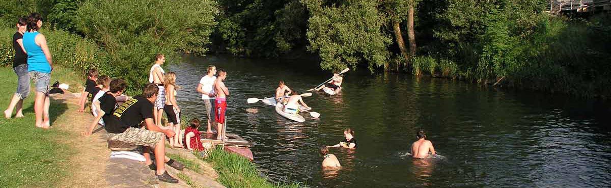 Badespaß Jugendliche beim Badespaß, links am Ufer Gruppe sitzend 2 plantschenden und 3 paddelnden Schülern zusehend